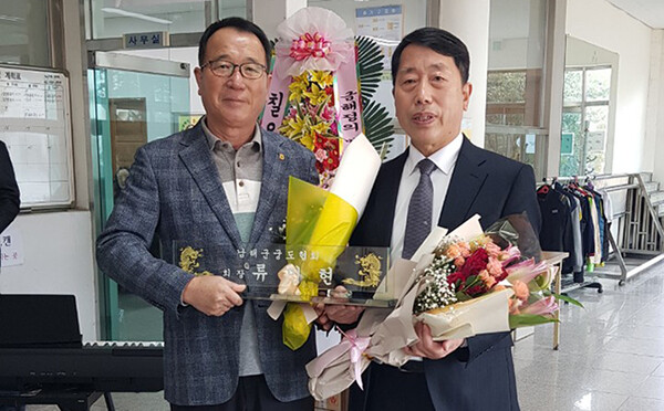 이임하는 박해동 회장이(왼쪽) 취임하는 류민현 회장에게 명패와 함께 꽃다발을 건네며 남해궁도 발전을 위해 노력해 주길 당부하고 있다